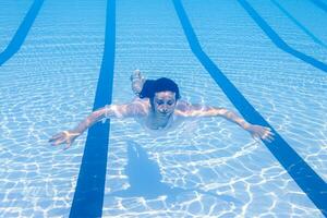 jung Mädchen im Badeanzug schwebend auf azurblau Wasser von Schwimmen Schwimmbad im Sonnenlicht foto