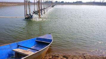 selektiv Fokus beim Boot mit Belüfter mehrere Turbine Räder auf Wasser Oberfläche im Garnele Teich Bauernhof foto