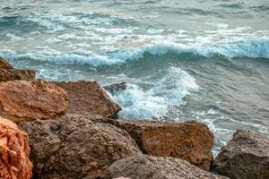 Mittelmeer Winter stürmisch Strand. schließen oben Wasser mit Steine auf das Strand foto