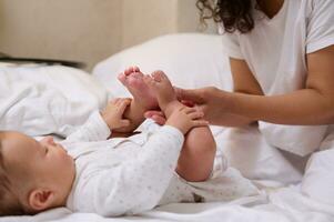 Nahansicht jung Mutter massieren Füße und Zehen von ihr Neugeborene Baby, genießen glücklich Zeit zusammen Baby Pflege und Kindheit foto