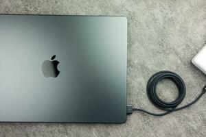 Bangkok, Thailand - - Dezember 24, 2023 MacBook Profi mit schwarz Laden Kabel eingesteckt in ein Verbinder foto
