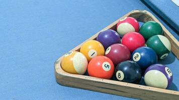 Billard- Bälle im ein hölzern Box auf ein Blau Billard- Tabelle foto