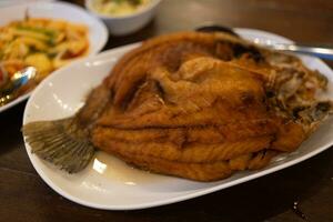 tief gebraten Fisch, Meer Bass mit Fischsoße auf das Weiß Teller foto