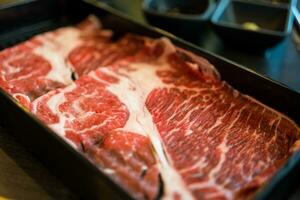 frisches Rindfleisch roh in Scheiben geschnitten mit marmorierter Textur, serviert für Sukiyaki. foto