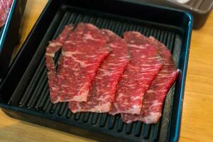 Prämie dünn geschnitten Rindfleisch im schwarz Tablett auf Holz Tabelle foto