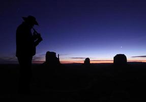 Mann spielt Flöte in der Wüste in der Abenddämmerung foto