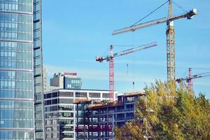 hoch erhebt euch Gebäude unter Konstruktion. Installation von Glas Fassade Paneele auf ein verstärkt Beton Struktur. foto