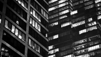 Muster von Büro Gebäude Fenster beleuchtet beim Nacht. Glas die Architektur , Unternehmen Gebäude beim Nacht - - Geschäft Konzept. schwarz und Weiß. foto