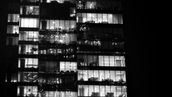 Muster von Büro Gebäude Fenster beleuchtet beim Nacht. Glas die Architektur , Unternehmen Gebäude beim Nacht - - Geschäft Konzept. schwarz und Weiß. foto