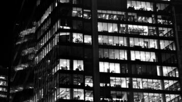 Muster von Büro Gebäude Fenster beleuchtet beim Nacht. Glas die Architektur , Unternehmen Gebäude beim Nacht - - Geschäft Konzept. schwarz und Weiß. foto