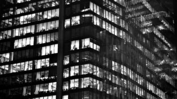 Muster von Büro Gebäude Fenster beleuchtet beim Nacht. Glas die Architektur , Unternehmen Gebäude beim Nacht - - Geschäft Konzept. schwarz und Weiß. foto