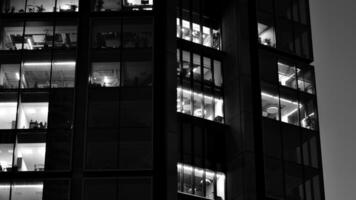 Muster von Büro Gebäude Fenster beleuchtet beim Nacht. Glas die Architektur , Unternehmen Gebäude beim Nacht - - Geschäft Konzept. schwarz und Weiß. foto