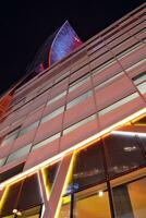 Fragment von das Glas Fassade von ein modern korporativ Gebäude beim Nacht. modern Glas Büro im Stadt. groß glühend Fenster im modern Büro Gebäude beim Nacht, im Reihen von Fenster Licht leuchtet. foto