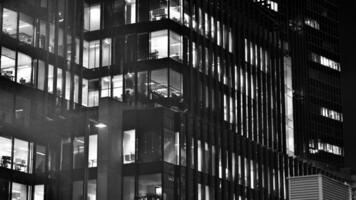 Muster von Büro Gebäude Fenster beleuchtet beim Nacht. Glas die Architektur , Unternehmen Gebäude beim Nacht - - Geschäft Konzept. schwarz und Weiß. foto