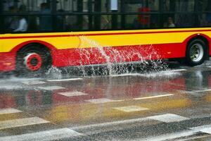 spritzt von unter das Räder von das Bus während schwer Regen. verschwommen Bus. foto