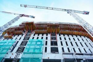 hoch erhebt euch Gebäude unter Konstruktion. Installation von Glas Fassade Paneele auf ein verstärkt Beton Struktur. foto