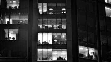 Muster von Büro Gebäude Fenster beleuchtet beim Nacht. Glas die Architektur , Unternehmen Gebäude beim Nacht - - Geschäft Konzept. schwarz und Weiß. foto