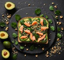 ai generiert Avocado Toast mit Lachs, Spinat und Kiefer Nüsse auf schwarz Hintergrund foto