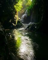 Besuch das Charme von Indonesien mit das lorong watu Wasserfall, Norden Bengkulu. ein eng Gasse gefüttert mit Stein Wände, das Morgen Licht scheint auf das Wasserfall foto