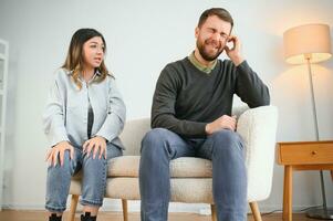 Familie Streit, Mann und Frau Sitzung auf Sofa beim heim. wütend Frau Geschrei beim ihr Mann foto