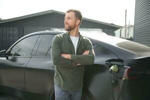 ein Mann Gebühren seine modern elektrisch Wagen. das Konzept von Grün Energie foto