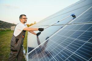 Fachmann Arbeiter Reinigung Solar- pv Tafel. Mann Herstellung sicher Solar- Batterien im gut Bedingung foto