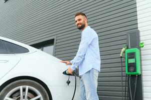 stilvoll Mann Einsätze Stecker in das elektrisch Auto Laden Steckdose foto