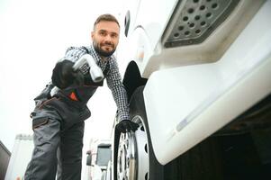 Arbeiten mit beschädigt Reifen. jung LKW Treiber ist mit seine Fahrzeug beim tagsüber foto