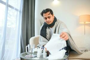 Gesundheit, kalt und Menschen Konzept - - krank jung indisch Mann im Decke haben Kopfschmerzen oder Fieber beim Zuhause foto