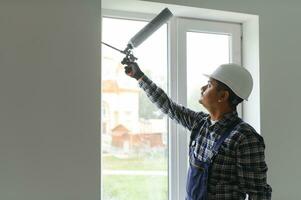 indisch Arbeiter mit ein Silikon Tube zum reparieren von Fenster Innen- foto