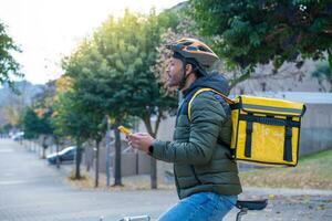 Lieferung Mann auf Fahrrad suchen Geographisches Positionierungs System Ort im das Telefon. schwarz Kurier liefern Essen und trinken. foto