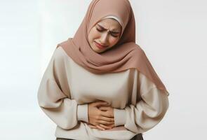 ai generiert asiatisch Muslim Frau im Hijab mit Hände halten Bauch mit Schmerzen Gesichts- Ausdruck isoliert Weiß Hintergrund foto