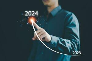 Geschäftsmann Hand zeichnet Linie zum zunehmend Pfeil von 2023 zu 2024, Neu Ziele, Pläne und Visionen zum Nächster Jahr 2024, Vorbereitung fröhlich Weihnachten und glücklich Neu Jahr Konzept. Neu Geschäft. foto