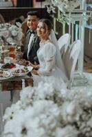 das Braut und Bräutigam feiern das Hochzeit im ihr Sitze. alles ist fast bereit zum das Hochzeit Zeremonie. Hochzeit Bankett foto