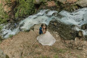 Hochzeit Paar ist umarmen in der Nähe von das Berg Fluss. Bräutigam und Braut . Natur Hochzeit Foto-Shooting. Foto Session im das Wald von das Braut und Bräutigam.