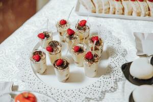 Süßigkeiten Bar. Tabelle mit Süßigkeiten, Süßigkeiten, Nachtisch. Kuchen und Beeren im das Süßigkeiten Bar. Süßigkeiten Bar mit köstlich Mini Kuchen, selektiv Fokus foto