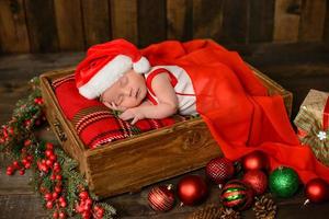 kleines neugeborenes mädchen acht tage alt im weihnachtsanzug foto