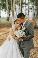 Braut und Bräutigam auf das Hintergrund von ein Märchen Wald. königlich Hochzeit Konzept. das Bräutigam umarmt das Braut. Zärtlichkeit und Ruhe foto