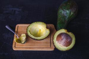 Avocadofrucht halbiert auf schwarzem Holzhintergrund foto