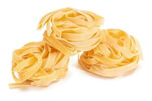 drei klassisch Italienisch roh Ei Fettuccine - - isoliert auf Weiß Hintergrund. trocken verdrehte ungekocht Pasta. Italienisch Kultur und Küche. roh golden Makkaroni Muster - - Isolierung foto