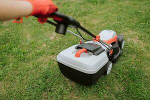 Rasen Mover auf Grün Gras im modern Garten. Maschine zum Schneiden Rasenflächen. Sicherheit Ausrüstung mit Garten Werkzeuge foto