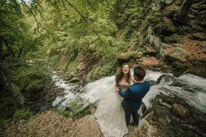 glücklich Hochzeit Paar auf das Kante von ein Wasserfall. Bräutigam und Braut. Hochzeit Foto Session im Natur. Foto Session im das Wald von das Braut und Bräutigam.