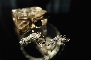 Hochzeit Foto Einzelheiten. Parfüm und elegant Silber Ohrringe und Hochzeit Ring von das Braut auf ein Glas Tisch. schön Licht. Betrachtung Luxus Zubehör