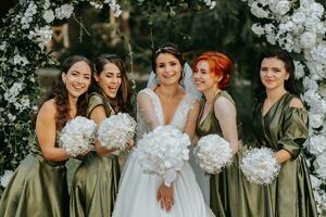 Brautjungfern lächelnd zusammen mit das Braut. das Braut und ihr Spaß freunde feiern das Hochzeit nach das Zeremonie im passend Kleider. Braut und freunde im Natur foto