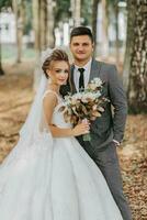 Braut und Bräutigam auf das Hintergrund von ein Märchen Wald. königlich Hochzeit Konzept. das Bräutigam umarmt das Braut. Zärtlichkeit und Ruhe. Porträt Foto