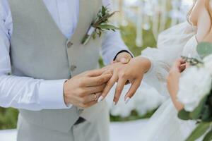 Jungvermählten beim das Hochzeit Zeremonie. das Bräutigam setzt auf das Braut Hochzeit Ring. hoch Qualität Foto. Frühling Hochzeit foto