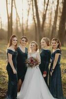 Braut mit Brautjungfern auf das Park auf das Hochzeit Tag. Brautjungfern im Blau Kleider und Braut halten schön Blumensträuße. schön Luxus Hochzeit Blog Konzept. Sommer- Hochzeit. foto