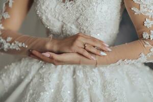 Porträt. ein Brünette Braut im ein Hochzeit Kleid mit lange Spitze Ärmel und ein schick Krone ist Stehen, posieren. abgeschnitten Foto. Herrlich bilden und Haar. voluminös Schleier. Hochzeit Foto. schön Braut foto