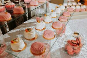 ein köstlich Hochzeit. Süßigkeiten Bar zum ein Bankett. Feier Konzept. modisch Nachspeisen. Tabelle mit Süßigkeiten, Süßigkeiten. Süßigkeiten Bar im Rosa Stil foto