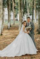 Braut und Bräutigam auf das Hintergrund von ein Märchen Wald. königlich Hochzeit Konzept. das Bräutigam umarmt das Braut. Zärtlichkeit und Ruhe. in voller Länge Porträt Foto